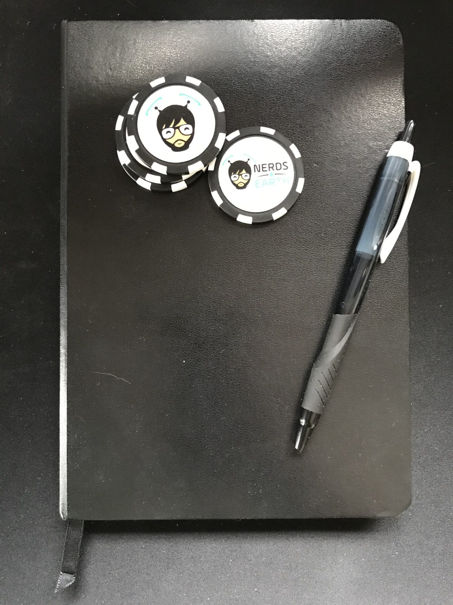 Abram's journal of game design, a little black book, complete with pen and Nerds on Earth poker chips.